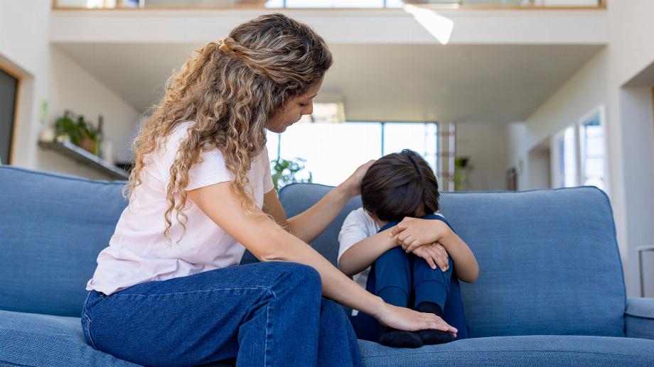 Une mère latino-américaine aimante réconfortant son fils triste à la maison alors qu'elle était assise dans le salon - concepts d'intimidation
