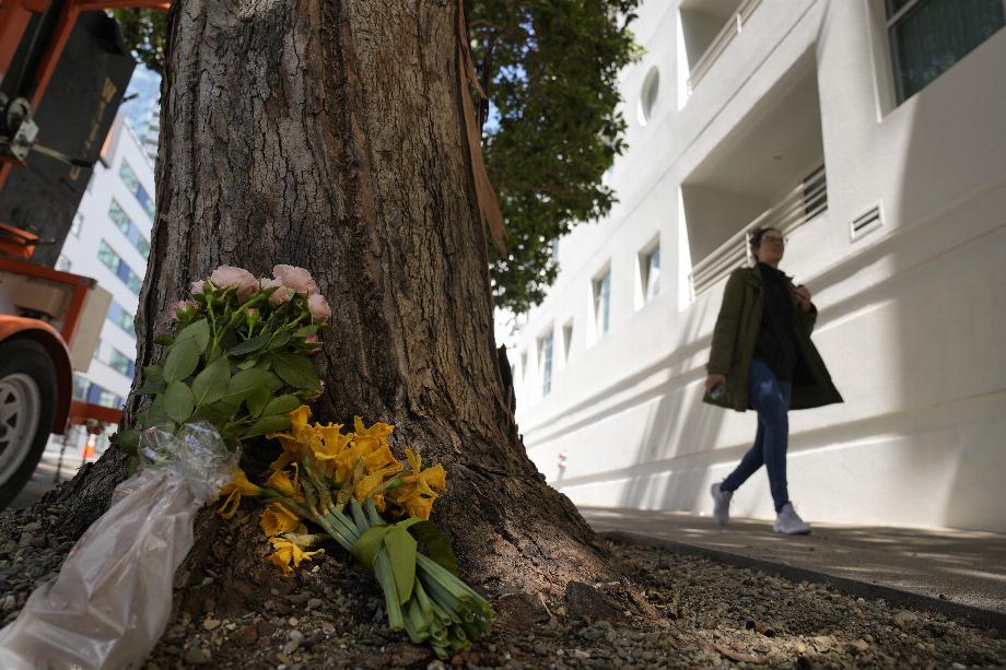 Une femme passe devant des fleurs laissées devant un immeuble à San Francisco, le mercredi 5 avril 2023, où Bob Lee, un responsable technologique qui a créé Cash App, a été mortellement poignardé. (AP Photo/Eric Risberg)