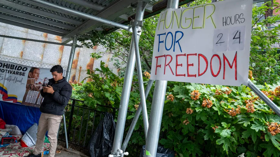 Prado regarde son téléphone devant une affiche disant "Faim pour la liberté" devant le siège des Nations Unies à New York (EFE/Ángel Colmenares) 
