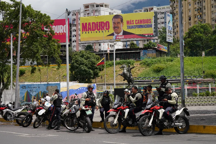 Policiers vénézuéliens attendent des ordres près d'une affiche publicitaire de la campagne de Maduro à Caracas (REUTERS/Alexandre Meneghini/Archive)