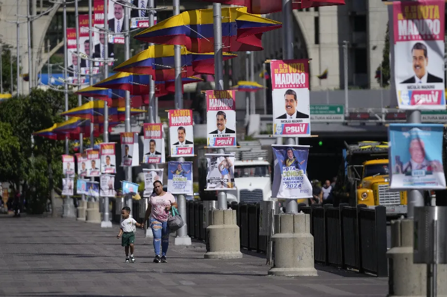 Une femme et son fils marchent dans une rue pleine d'affiches de campagne de Maduro à Caracas (Photo AP/Fernando Vergara)