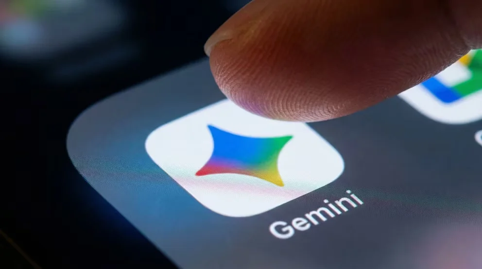 Gros plan d'un doigt sur le point de toucher l'icône de l'application Gemini sur l'écran d'un smartphone, mettant en valeur le logo coloré et l'avancement technologique de l'intelligence artificielle mobile.