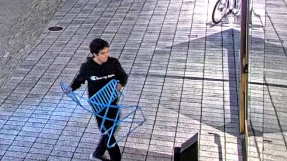 Une image de vidéosurveillance montre un homme portant un sweat à capuche sombre, identifié comme Sam Altman, marchant avec une chaise en métal bleue